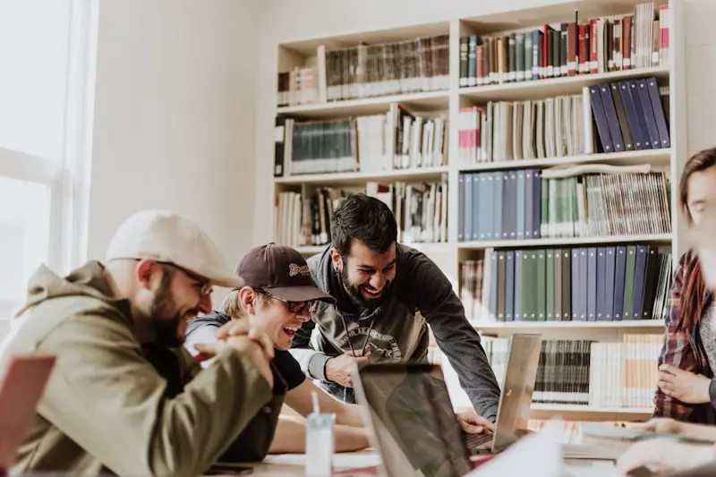 Grupo de jóvenes riendo juntos alrededor de una mesa en una biblioteca
