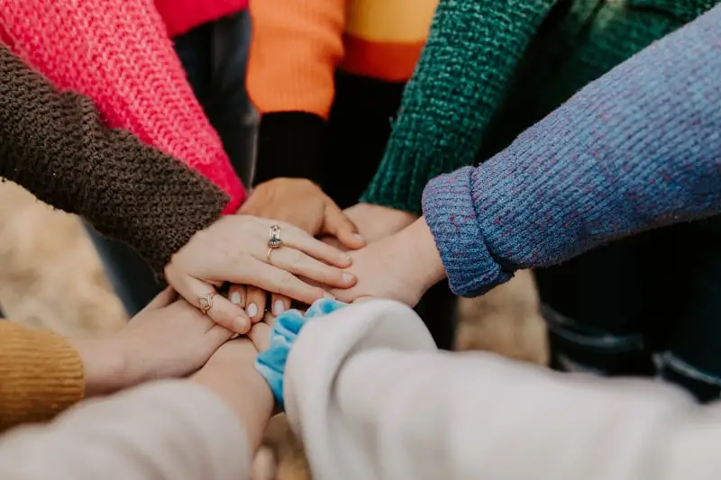 Manos de un grupo de jóvenes unidas en el centro de un círculo